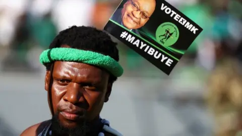 reuters A supporter of former South African President Jacob Zuma's new political party, uMkhonto we Sizwe, wears a pamphlet during the launch of its election manifesto ahead of a general election on May 29, at a rally in Soweto, South Africa, May 18, 2024