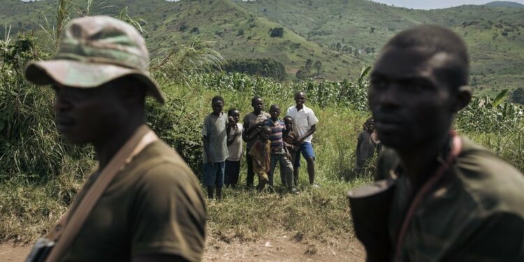 Children look at FARDC (Armed Forces of the DRC) soldiers riding in a vehicle in a military position in Mirangi, close to the frontline and the town of Kibirizi, controlled by the M23 rebellion, North Kivu province, eastern Democratic Republic of Congo, in May 2024. (Alexis Huguet/AFP)