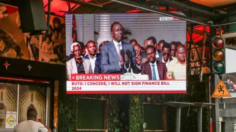  James Wakibia/Getty Images A man watches as President William Ruto gives a televised address at State House in Nairobi 