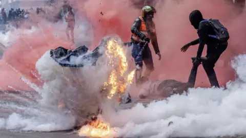 AFP A tear gas canister explodes as protesters try to help injured people outside the Kenya Parliament during a nationwide strike to protest against tax hikes and the Finance Bill 2024 in downtown Nairobi, on June 25, 2024