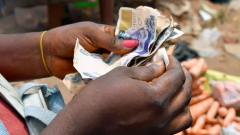 AFP A market vendor with painted nails counts naira in south-eastern Nigeria - 2023