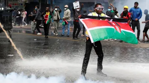 Reuters  demonstrator holds a Kenyan flag as police use water cannons and tear gas to disperse protesters during a demonstration against Kenya's proposed finance bill 2024/2025 in Nairobi, Kenya, June 25, 2024.