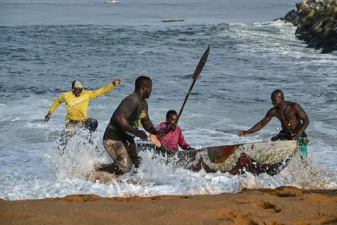ISSOUF SANOGO/AFP Fishermen bring their canoe in from the sea.