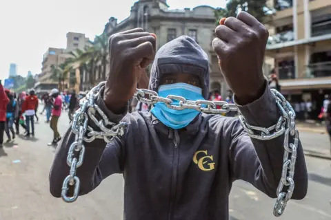 BONIFACE MUTHONI/GETTY IMAGES  A protester with both hands tied with a chain takes part in an anti-government protest on 2 July.