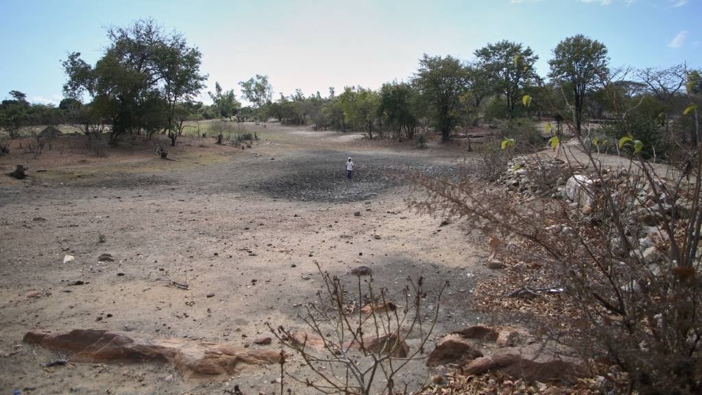 Farmer Takesure Chimbu walks on the dry bed of the