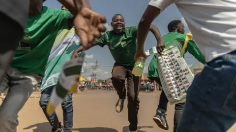 AFP Supporters of the Democratic Green Party dance as they attend the party's political rally in Gihara, Rwanda, on June 23, 2024, ahead of Rwanda's upcoming parliamentary and presidential elections.