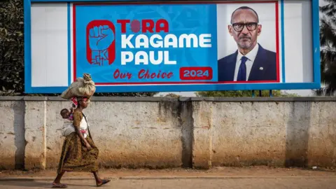 AFP  A woman carrying her baby on her back walks past an electoral billboard asking for the vote for the incumbent President of Rwanda and the ruling Rwandan Patriotic Front (RPF) presidential candidate Paul Kagame in Kigali, on July 11, 2024