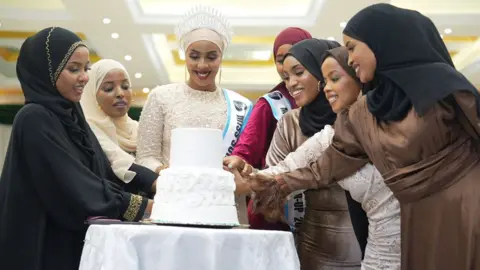 Shukri Mohamed Abdi A group of women cutting a cake