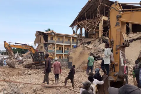 AFP People and excavators on site Saints Academy in Jos.