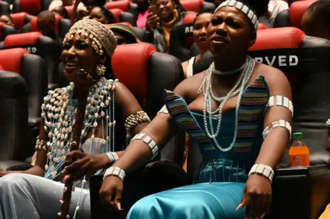 OUPA BOPAPE/GETTY IMAGES Two women smile and frown in a cinema.