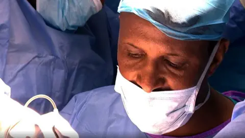 A surgeon in a mask at the operating table