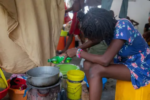 Getty Images  A woman cooks in a room at a refugee camp in Port-au-Prince.