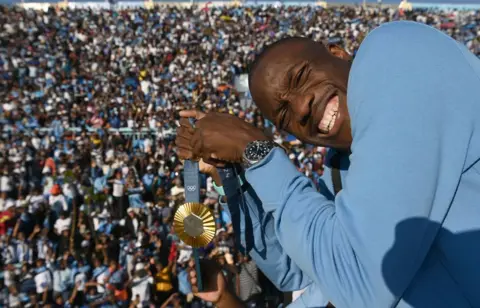  MONIRUL BHUIYAN / AFP  Letsile Tebogo poses with his gold Olympic medal in a stadium in Gaborone, Botswana.