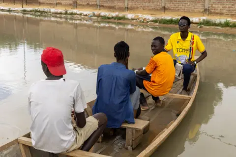 CHANCELIN MBAIRAMADJI MOITA/EPA People use a boat to move in a flooded street.