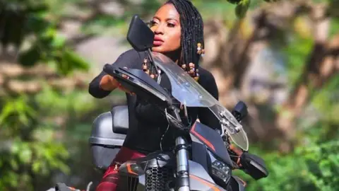 Udoh Ebaide Joy Ebaide sitting on top of her motorcycle 