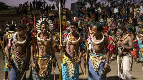 Emmanuel Croset / AFP Five members of a royal regiment hold long reeds in their hands and wear traditional dress, including material resembling animal skin wrapped around their waists, at a reed dancing ceremony at the Ludzidzini Royal Residence in Eswatini - Monday 2 September 2024