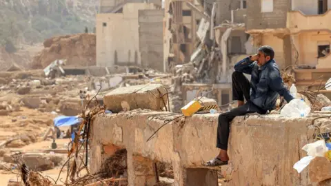 Getty Images A man reacts as he sits on the rubble of a destroyed building in Libya's eastern city of Derna on 18 September 2023 following deadly flash floods