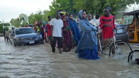 Gift Ufuoma / BBC People walking through a flooded street in Maiduguri, Nigeria - September 2024