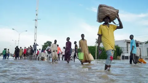 Gift Ufuoma / BBC People walking through a flooded street in Maiduguri, Nigeria - September 2024