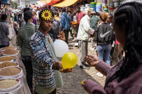 MICHELE SPATARI / AFP A street vendor with a flower ornament known as 'Adey Abeba' in his air sells a balloon.