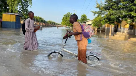  Ahmed Kingimi/Reuters A young Nigerian man wades through the deep waters caused by severe floods in Maiduguri, Nigeria - Tuesday 17 September 2024.