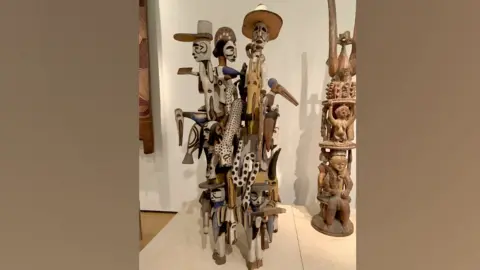 Adaobi Tricia Nwaubani Wooden stature featuring several figures on display at museum