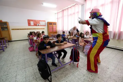 Billel Bensalem / AFP A clown performs in front of pupils in a classroom in Algeria September 22, 2024