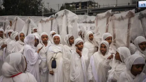 Michele Spatari / AFP Begena players (a traditional ten-stringed box-lyre instrument) cover their instruments from the rain during celebrations to mark the Ethiopian Orthodox holiday of Meskel, in Addis Ababa, on September 26, 2024.