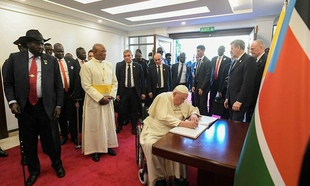 Pope Francis signing a book as President of South Sudan Salva Kiir, left, looks on at the Presidential Palace in Juba, South Sudan.