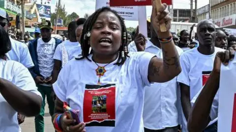 AFP Activists and athletes carry banners and chant slogans as they march through Eldoret, western Kenya, on September 13, 2024, to demonstrate against the murder of women in Kenya after Rebecca Cheptegei lost her life