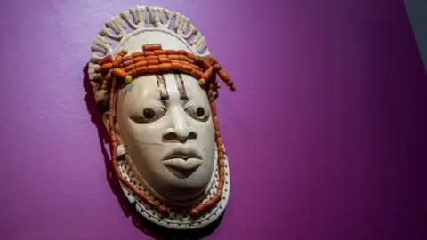 Getty Images A 19th-century ivory, ceremonial hip mask in honour of Queen Mother Idia and looted by British soldiers from the Kingdom of Benin in 1897 hangs on display in the 