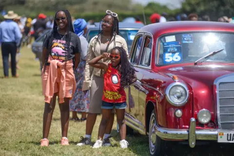 GERALD ANDERSON /  GETTY IMAGES Girls pose for a photo next to a red car - Sunday 29 September 2024