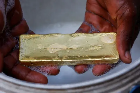 FRANCIS KOKOROKO / REUTERS A man handles a gold bar in a wash basin.