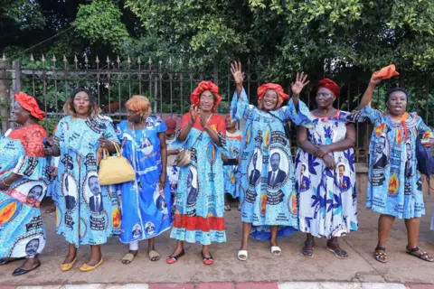 AFP Supporters of the ruling CPDM party cheer as they wait for President Paul Biya to drive past them.