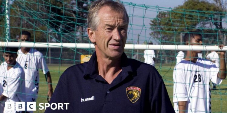 Roald Poulsen pictured in a blue Cape United polo shirt as three young players move a football goal behind him