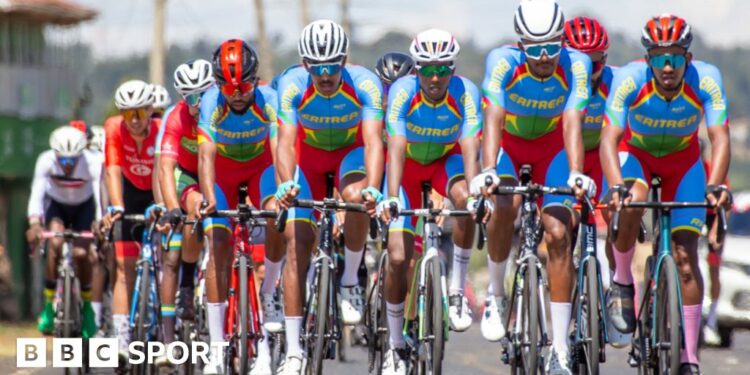 Eritrean cyclists and staff celebrate amid a giant Eritrean flag