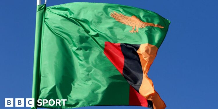 A Zambian flag flutters on a flagpole