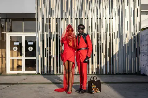 Olympia de Maismont / AFP A man and a woman dressed in red and black pose for a photograph as they arrive at the Federal Palace Hotel for Lagos Fashion Week on 26 October.