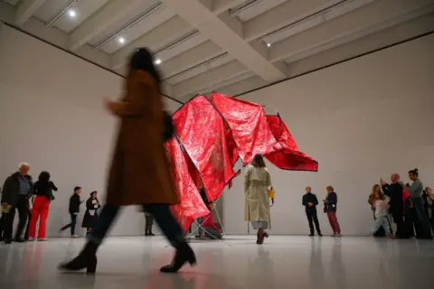 Jaap Arriens / Getty Images Visitors observe the red sculpture 