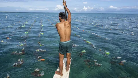 Earthshot Prize Man on a board in litter-strewn sea