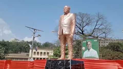 Citi Newsroom Front view of the statue of Nana Akufo-Addo, which is bronze in colour, seen on its marble pedestal. He is depicted wearing a suit, his glasses and is smiling. It is outside Effia-Nkwanta Regional Hospital in Sekondi, Ghana - November 2024