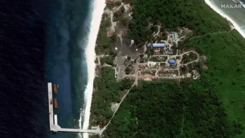 Maxar Close up satellite image of the jetty with ships alongside it; the image also shows development on the island