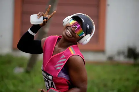 ADEKUNLE AJAYI / GETTY IMAGES A woman dressed in pink sports gear shows excitement during the ninth edition of the Lagos Women Run 2024, a 10km female road race.