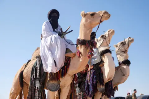 ESAM OMRAN AL-FETORI / REUTERS Men wearing traditional garb ride camels.