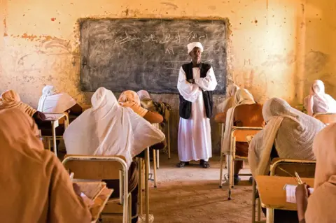 AFP A teacher stands at the front of a classroom while invigilating an examination.