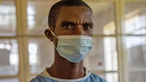 BBC A nurse in blue scrubs wearing a face mask in Lwiro community hospital, DR Congo