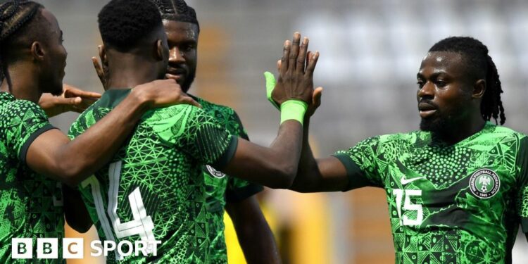 Moses Simon, wearing a green Nigeria jersey with the number 15 on it, is pictured giving a high five to team-mate Kelechi Iheanacho as the Super Eagles celebrate a goal