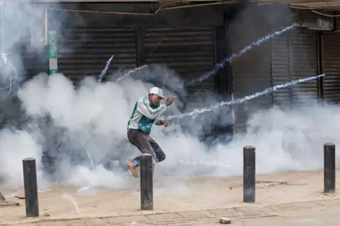 AFP A protester runs to get away from a detonating tear gas canister during a demonstration against the government in Nairobi, Kenya, on August 8, 2024