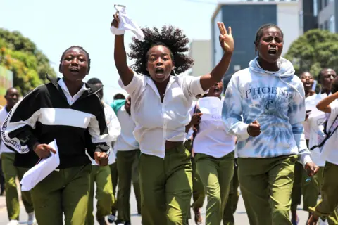 LUISA NHANTUMBO / EPA Teenagers in school uniform jog and chant.