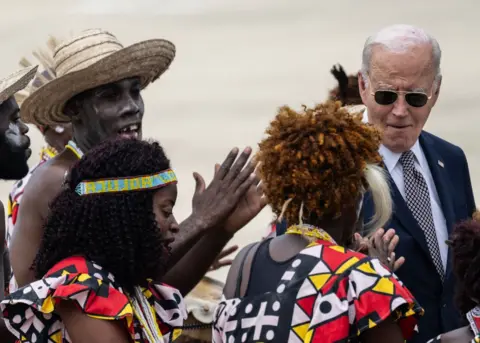 ANDREW CABALLERO-REYNOLDS / AFP US President Joe Biden (R) reacts to dancers as he walks along the tarmac.